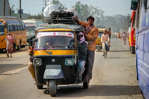 Gul taxi-tuktuk med många resenärer och mycket packning.