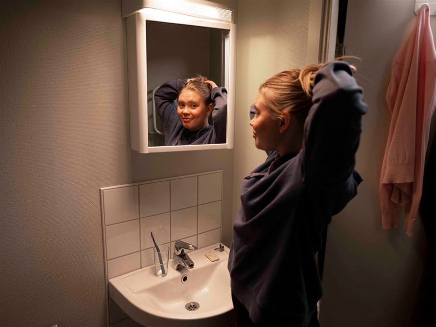 Student som står framför spegeln i sitt badrum i sin studentlägenhet.