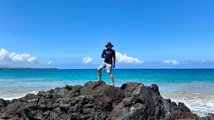 Forskaren Tristan McKenzie står på en klippa med havet som bakgrund 
