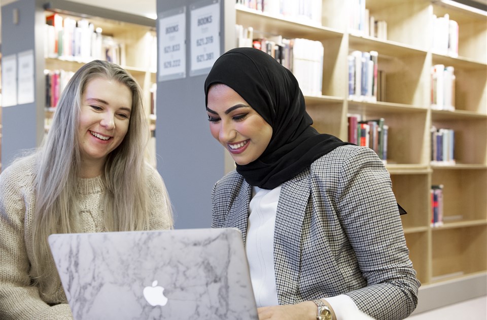 två kvinnliga studenter tittar på en dator