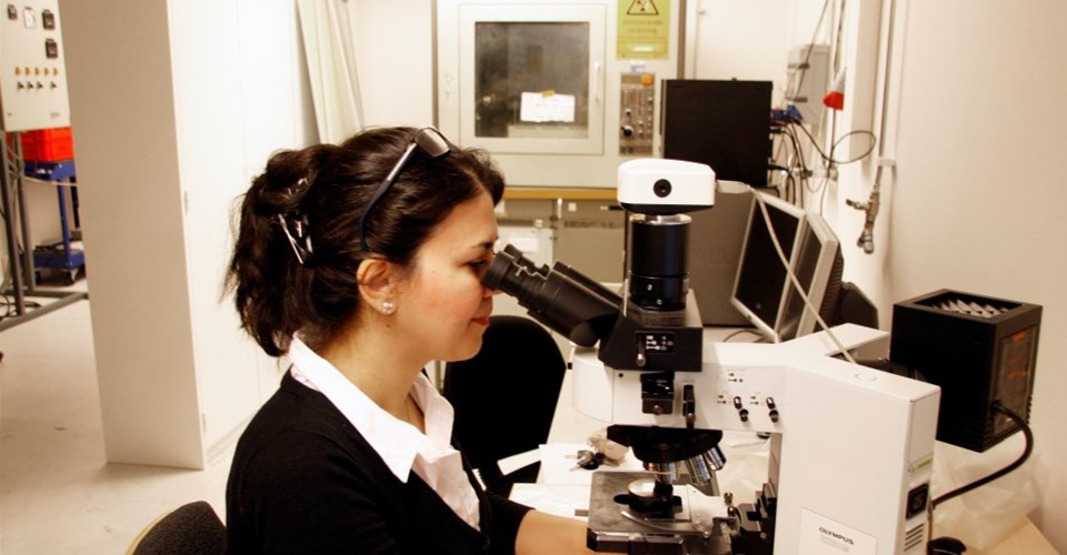 En kvinna som sitter vid ett mikroskop