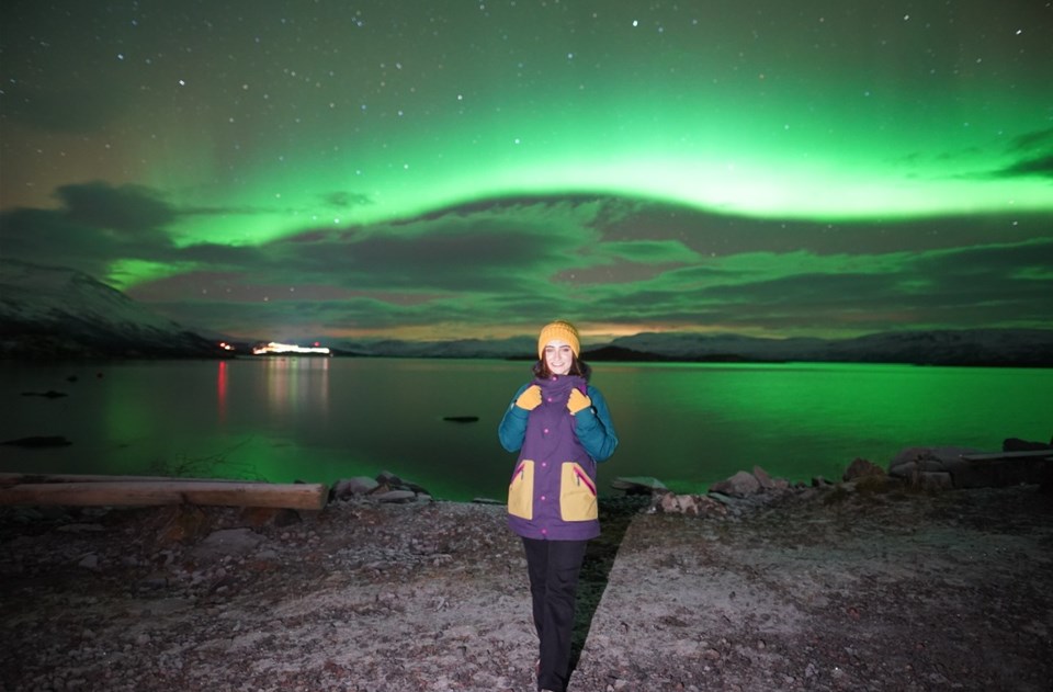 Woman in the night with northen lights behind her 