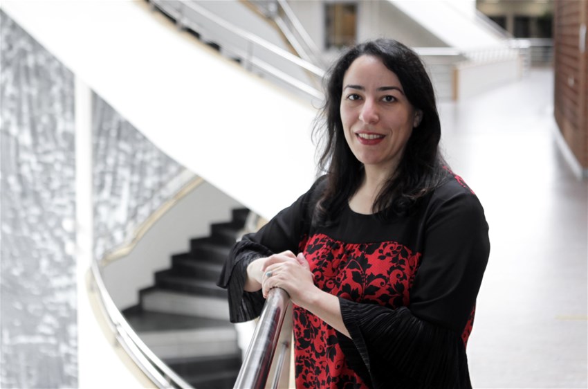 Samira, a woman, standing by a staircase.