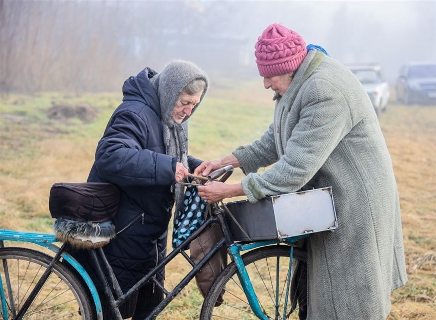 Ukrainska kvinnor lastar fältkamin på cykel