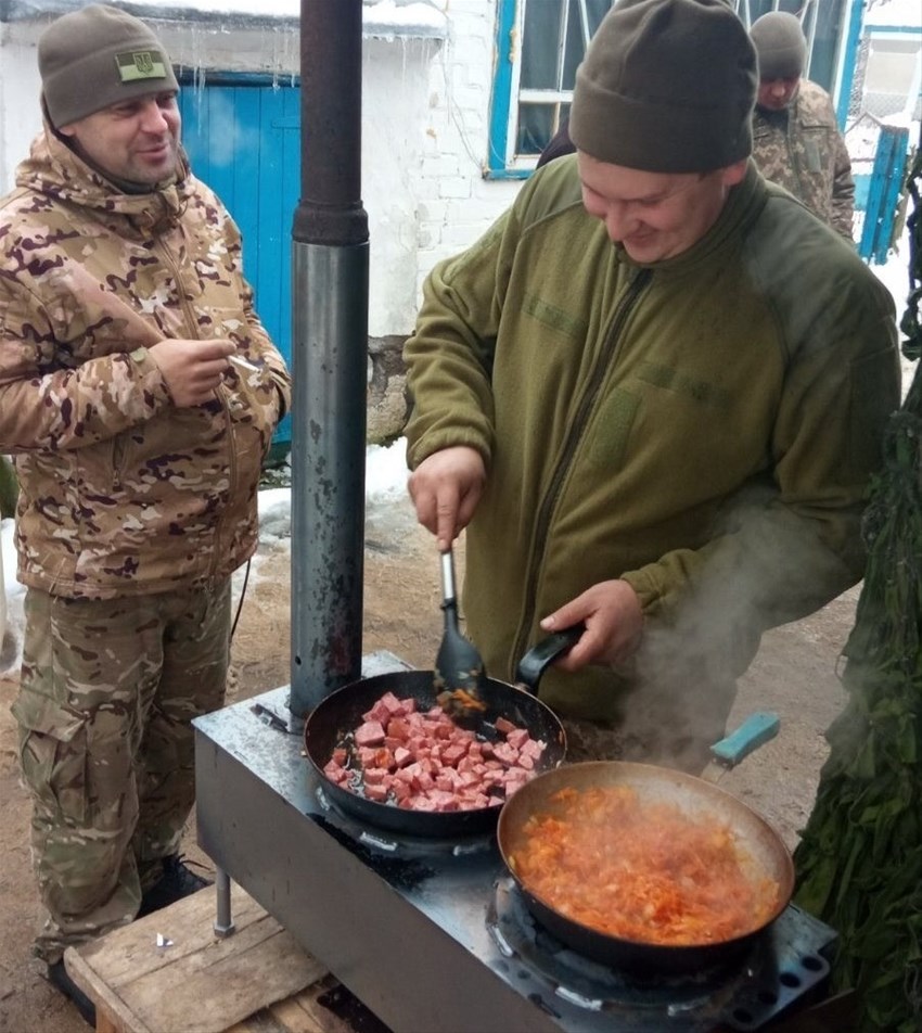 Soldater i Ukraina lagar mat på en fältkamin tillverkad i Sverige