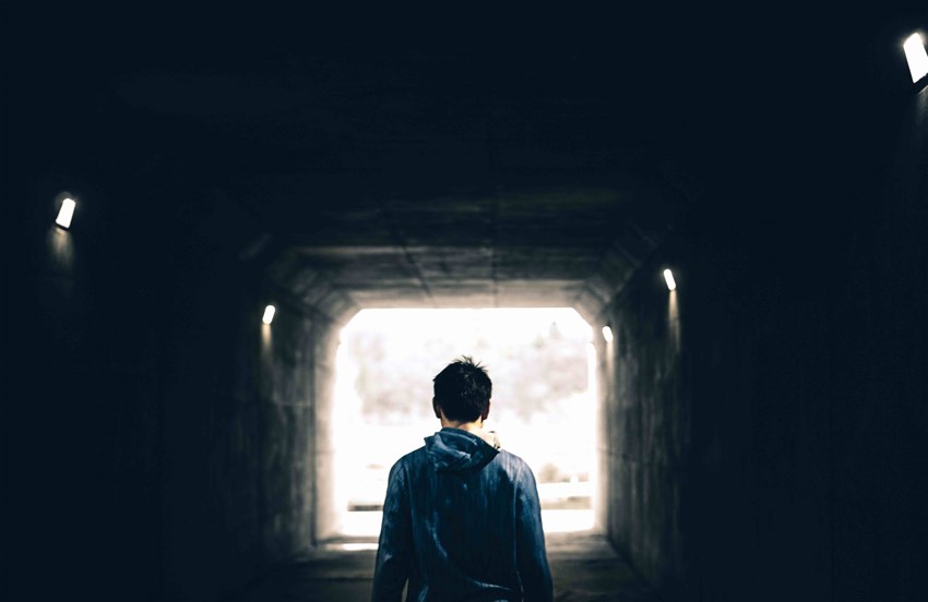 Ensam person syns bakifrån i mörk tunnel