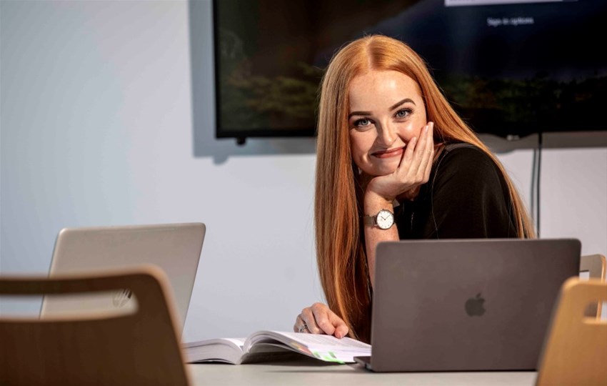 Foto på en student i studiemiljö med bok och dator