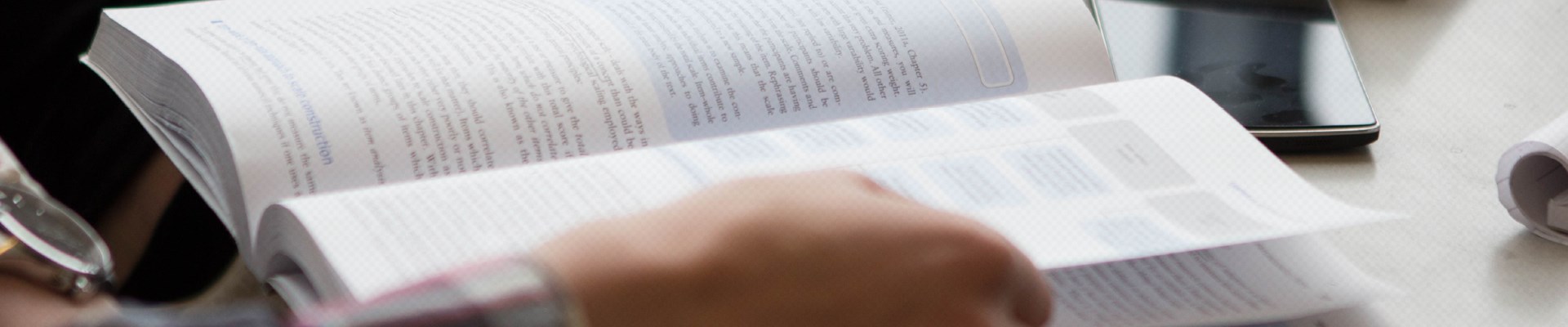 En hand som bläddrar i bok. Foto.