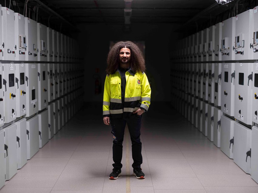 Alumn som står i arbetskläder i ett ställverk