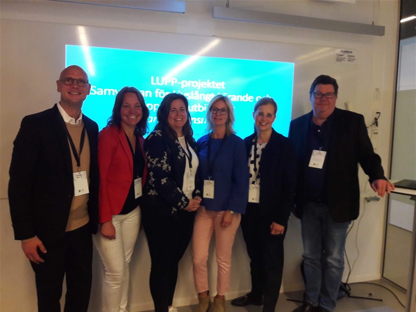 Bild på projektgruppen. De står på rad framför en presentation.