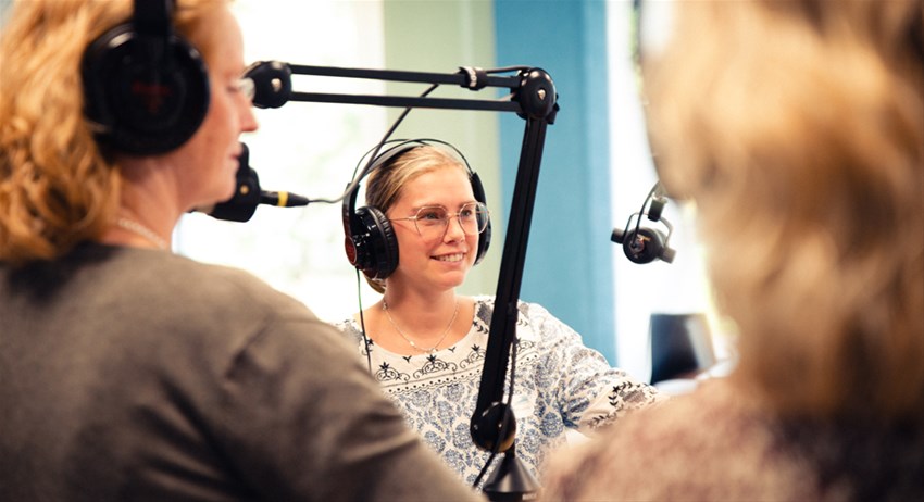 Deltagare på podd-workshop har hörlurar på sig