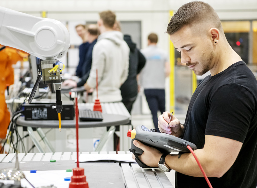 Studenter på Högskolan Väst arbetar i ett automationslabb med en robotar.