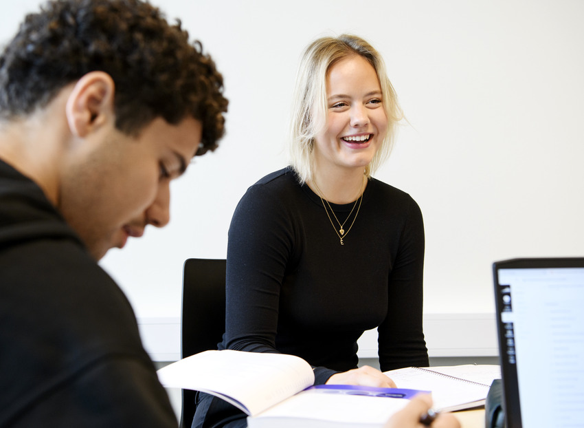 Studenter på Högskolan Väst sitter tillsammans med studiematerial och pluggar.