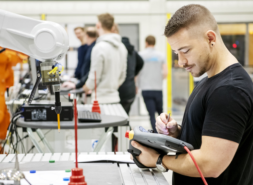 Studenter på Högskolan Väst arbetar i ett automationslabb med en robotar.