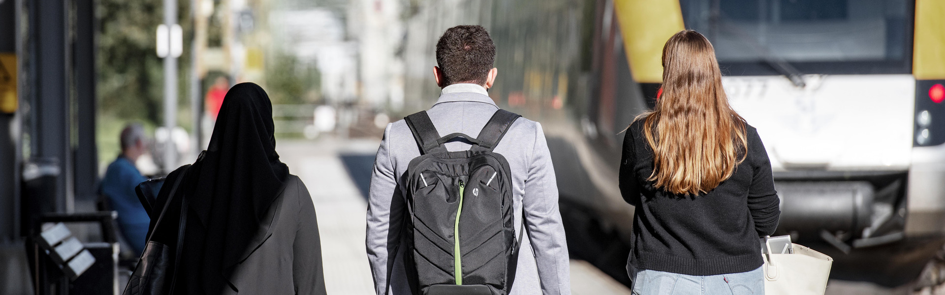Studenter från Högskolan Väst går på en perrong mot ett tåg.