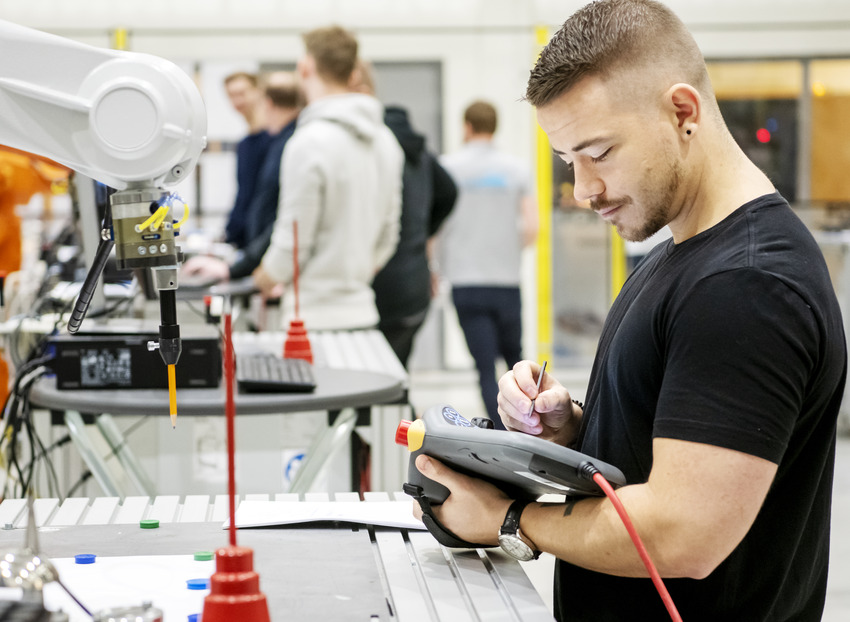 Studenter på Högskolan Väst arbetar i ett automationslabb med en robotar.