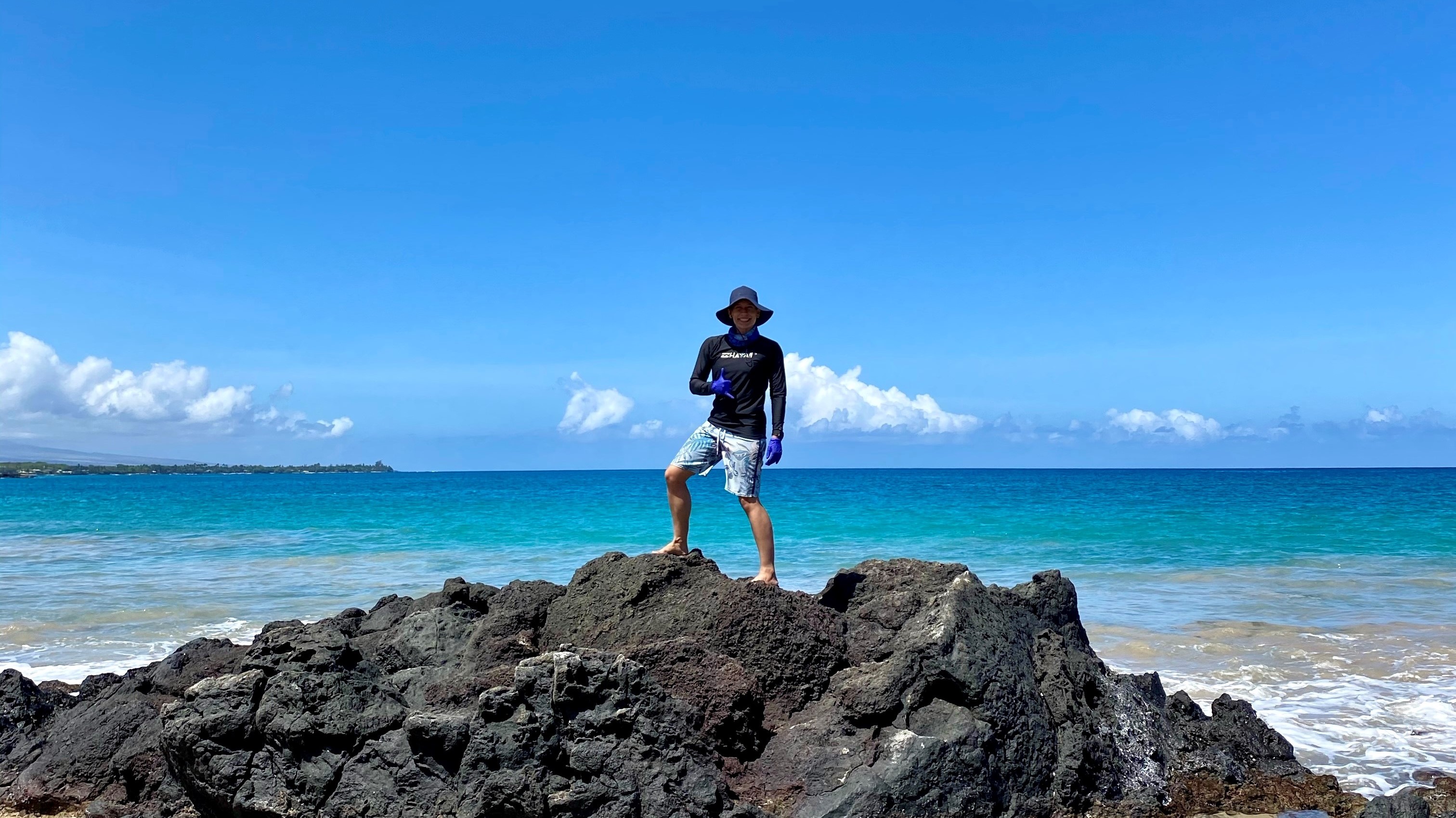 Forskaren Tristan McKenzie står på en klippa med havet som bakgrund 