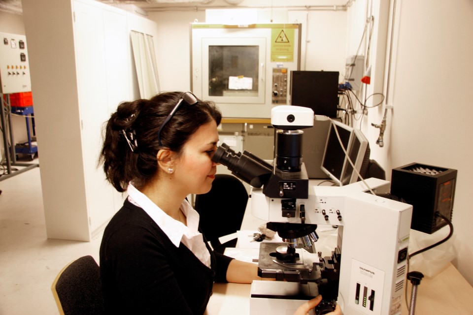 En kvinna som sitter vid ett mikroskop