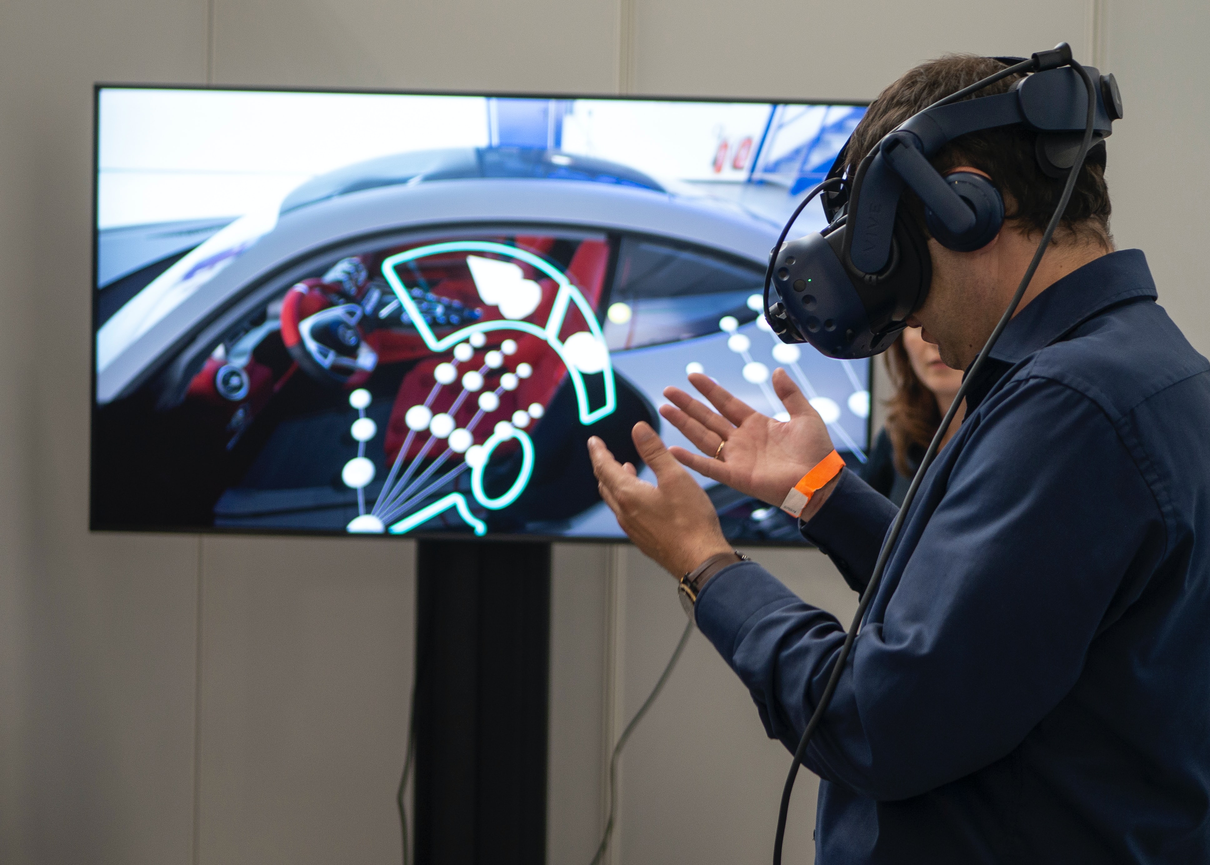 Person med VR-glasögon ståendes framför stor bildskärm