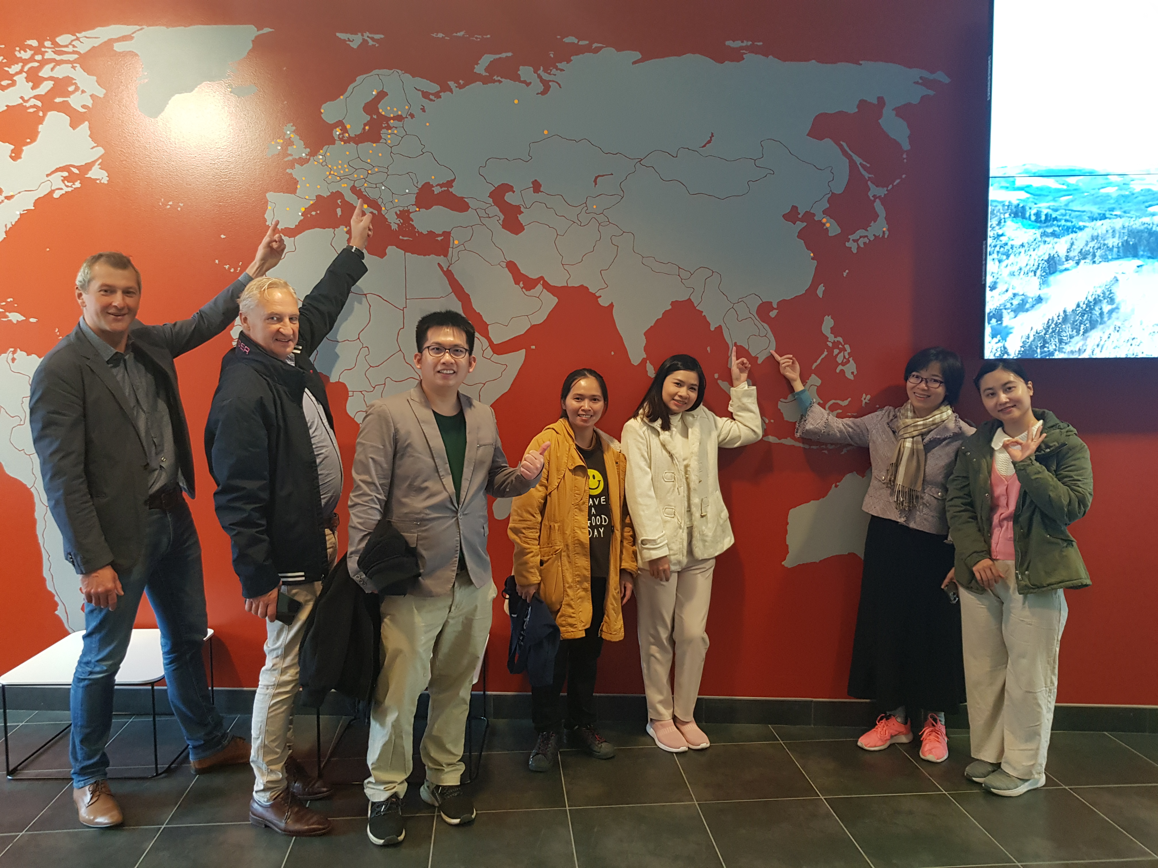 People standing by a red map on a wall 